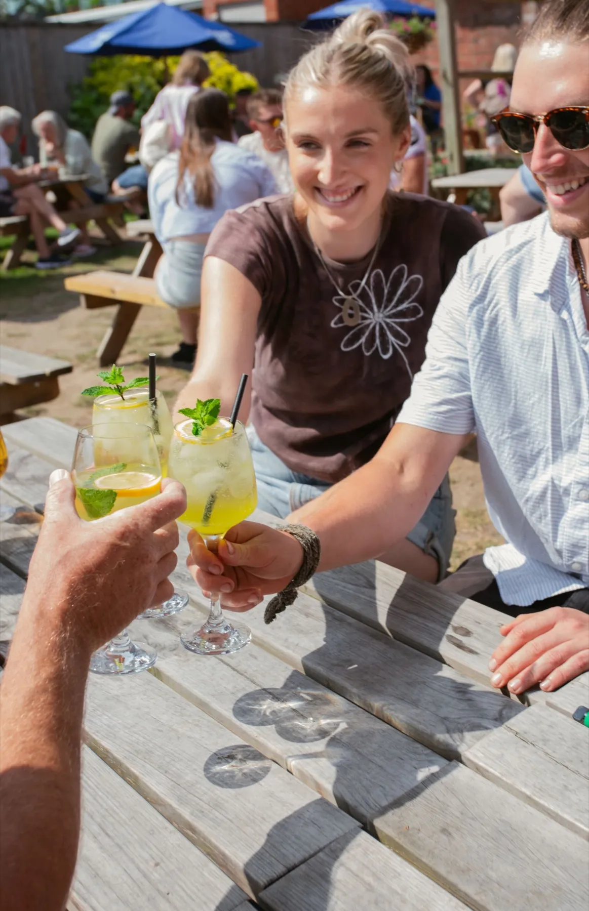 Friends raising drinks together in the garden at The Lord Raglan