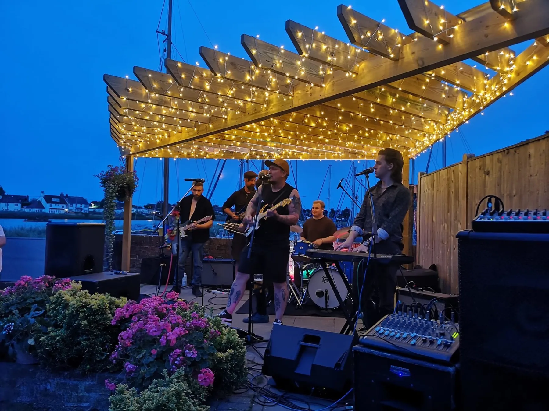 A live band playing under fairy lights in the waterside garden at The Lord Raglan, Emsworth